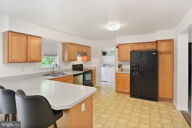 kitchen featuring black appliances, a sink, washer and clothes dryer, under cabinet range hood, and light countertops