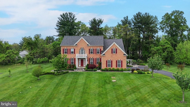 georgian-style home featuring a front yard and view of scattered trees
