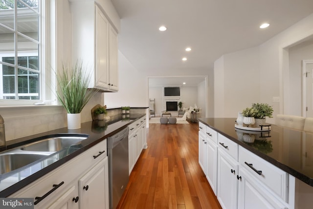 kitchen with stainless steel dishwasher, dark countertops, a sink, and recessed lighting