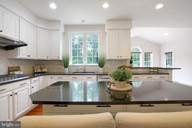 kitchen with a sink, dark countertops, stainless steel gas cooktop, tasteful backsplash, and white cabinetry