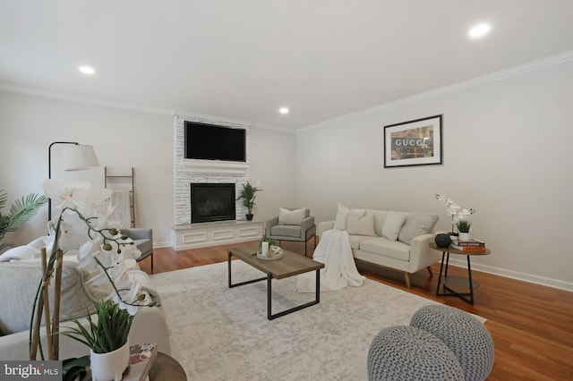 living room featuring ornamental molding, recessed lighting, wood finished floors, baseboards, and a stone fireplace