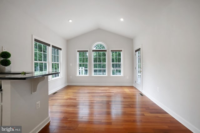 unfurnished living room featuring plenty of natural light, lofted ceiling, wood finished floors, baseboards, and recessed lighting