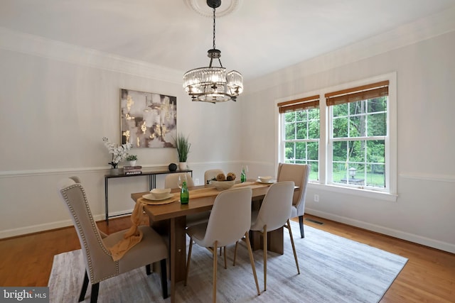 dining space with a chandelier, wood finished floors, baseboards, and crown molding
