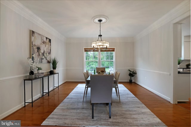 dining room with a chandelier, crown molding, wood finished floors, and baseboards
