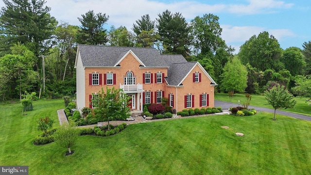 colonial inspired home featuring a front lawn and asphalt driveway