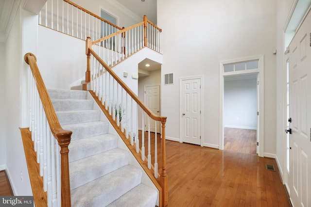 stairway with hardwood / wood-style flooring, a towering ceiling, and baseboards