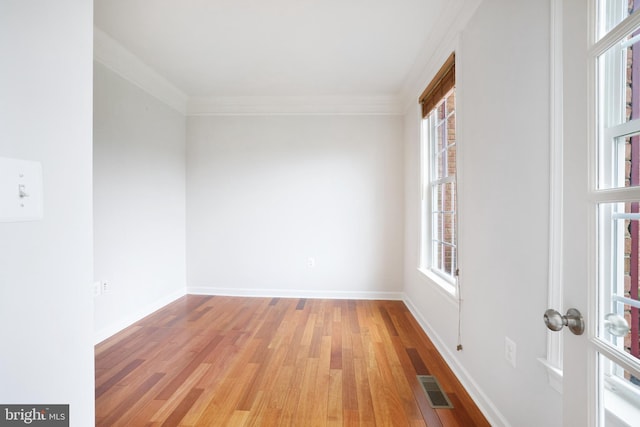 empty room with healthy amount of natural light, light wood-style flooring, ornamental molding, and baseboards