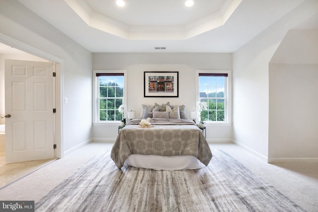 bedroom featuring a raised ceiling, multiple windows, light carpet, baseboards, and ornamental molding