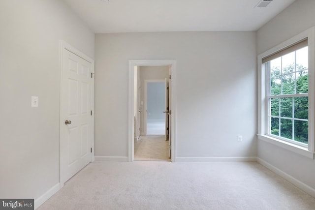 unfurnished bedroom featuring multiple windows, carpet flooring, and baseboards