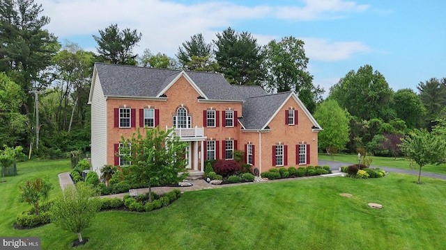colonial house with a front yard and brick siding