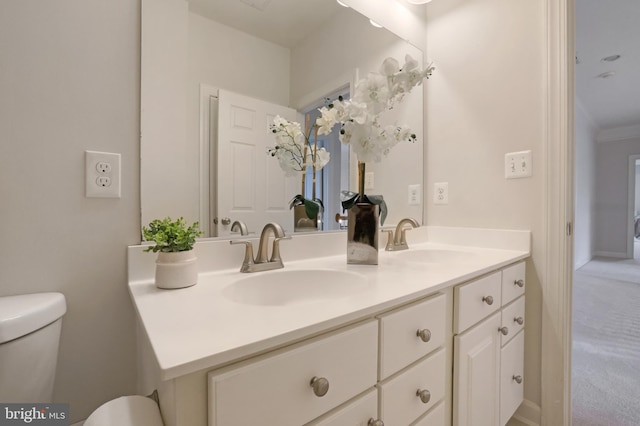 bathroom with toilet, double vanity, and ornamental molding
