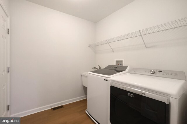 laundry area with wood finished floors, washer and dryer, and baseboards