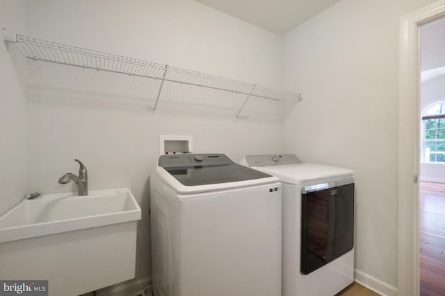 clothes washing area featuring independent washer and dryer, wood finished floors, and baseboards