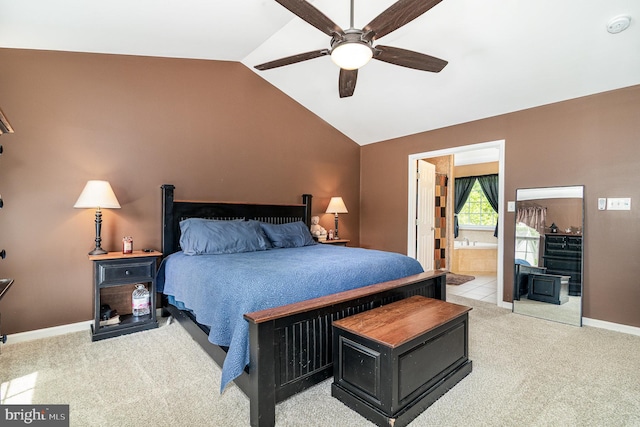 bedroom featuring light colored carpet, lofted ceiling, baseboards, ensuite bath, and ceiling fan