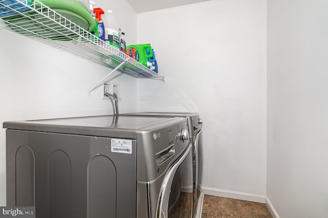 clothes washing area with independent washer and dryer and baseboards