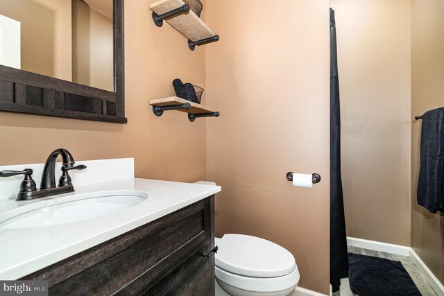bathroom featuring baseboards, toilet, and vanity
