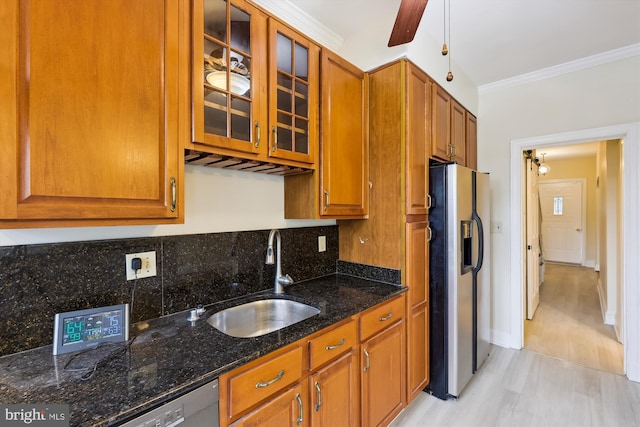 kitchen with stainless steel refrigerator with ice dispenser, a sink, ornamental molding, brown cabinetry, and tasteful backsplash