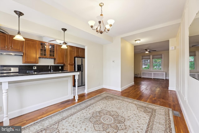 kitchen with stainless steel refrigerator with ice dispenser, brown cabinetry, dark wood finished floors, and dark countertops