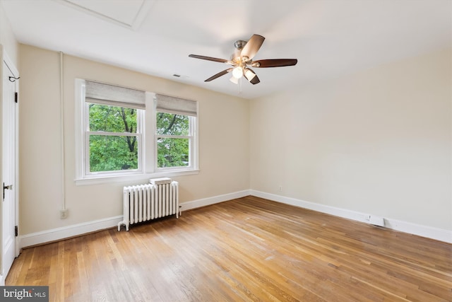 unfurnished room featuring radiator heating unit, light wood-style floors, baseboards, and a ceiling fan