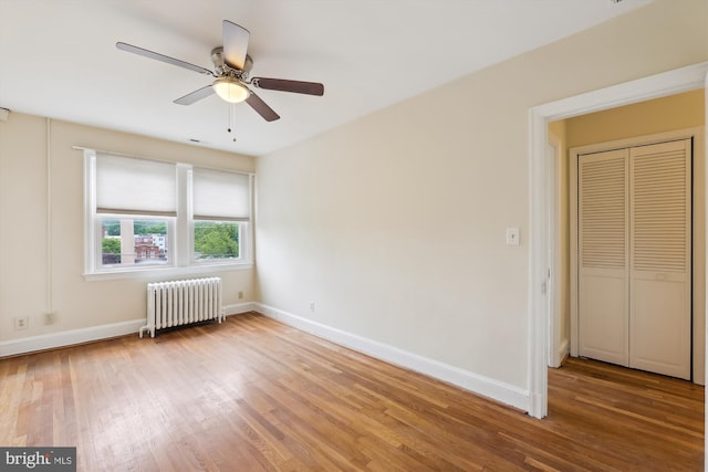 spare room featuring radiator heating unit, wood finished floors, baseboards, and ceiling fan