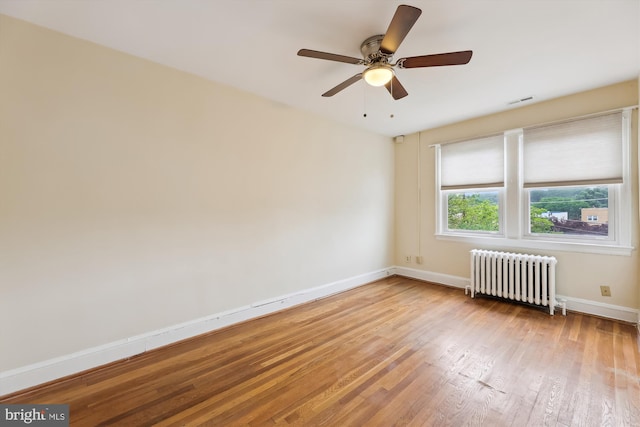 unfurnished room featuring radiator, light wood finished floors, baseboards, and a ceiling fan