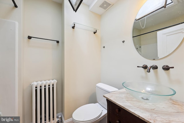 bathroom featuring radiator heating unit, toilet, and vanity
