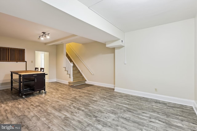 basement featuring wood finished floors, baseboards, and stairway