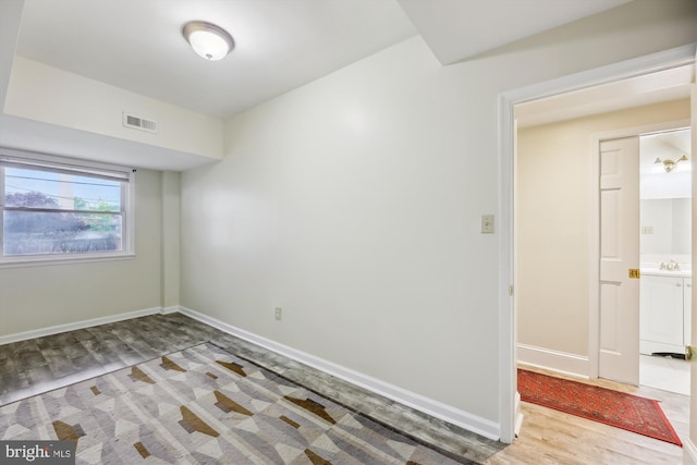 spare room featuring wood finished floors, baseboards, and a sink