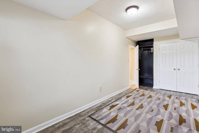 unfurnished bedroom with baseboards, wood finished floors, and a closet