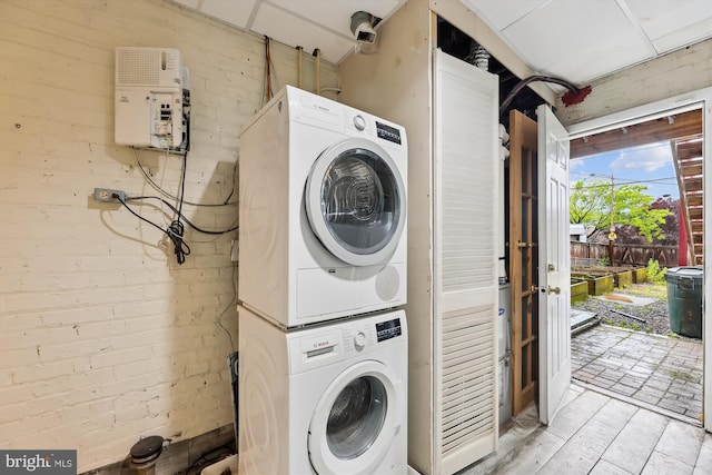 clothes washing area with stacked washer and clothes dryer and light wood-style flooring