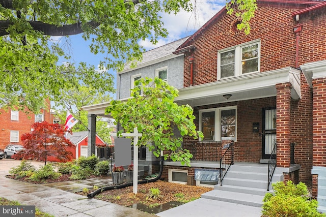 view of front of house with brick siding, a porch, and cooling unit