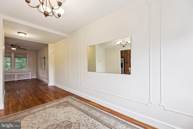 spare room featuring a chandelier, wood finished floors, and baseboards