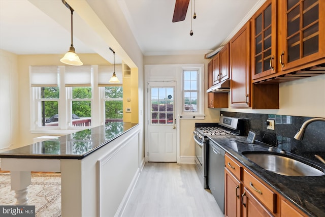 kitchen featuring stainless steel appliances, a sink, light wood-style flooring, brown cabinetry, and glass insert cabinets