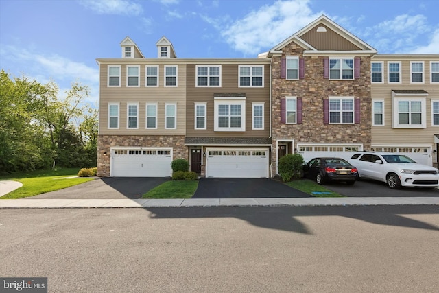 townhome / multi-family property featuring stone siding, driveway, and a garage