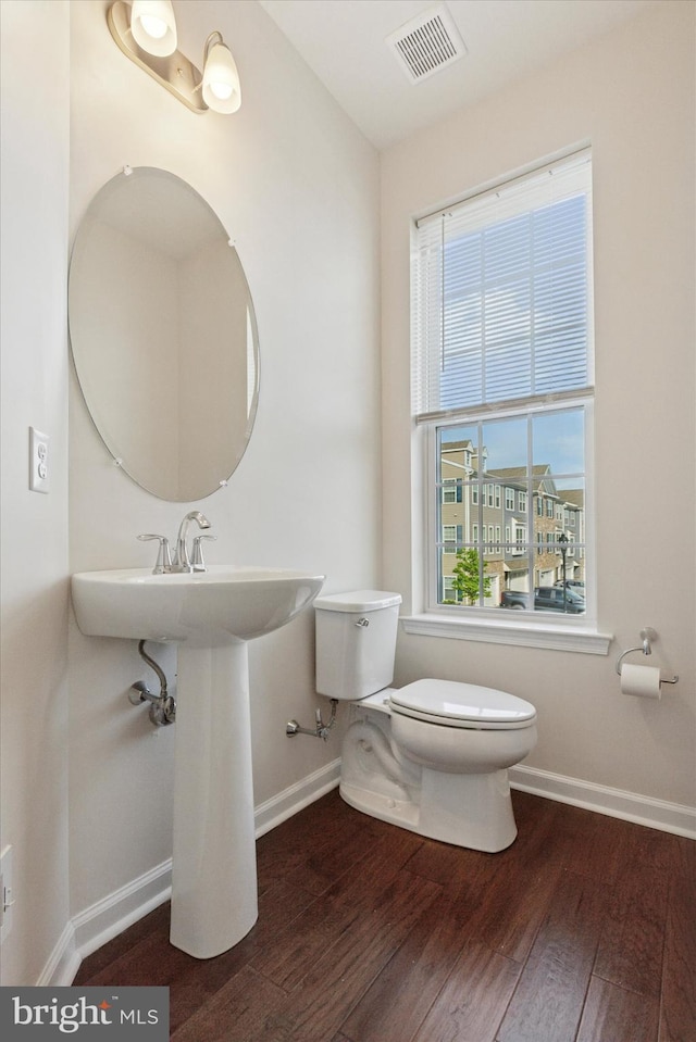 bathroom featuring toilet, wood finished floors, baseboards, and healthy amount of natural light