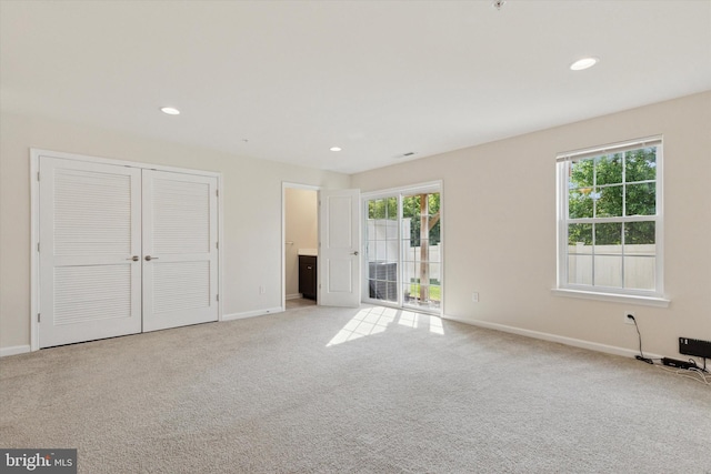 unfurnished bedroom featuring light carpet, baseboards, recessed lighting, and a closet