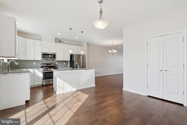 kitchen with appliances with stainless steel finishes, a chandelier, backsplash, dark wood-type flooring, and recessed lighting