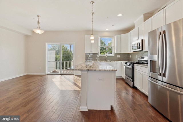 kitchen with stainless steel appliances, backsplash, a kitchen island, dark wood-type flooring, and hanging light fixtures