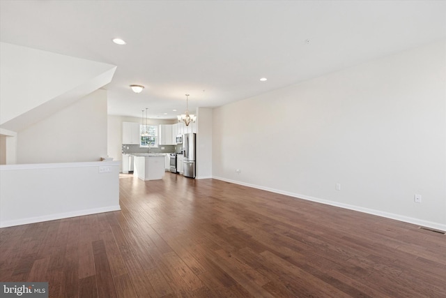 unfurnished living room featuring a chandelier, dark wood-style floors, recessed lighting, and baseboards