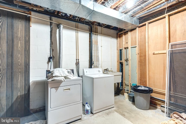 unfinished basement with independent washer and dryer, concrete block wall, and a sink