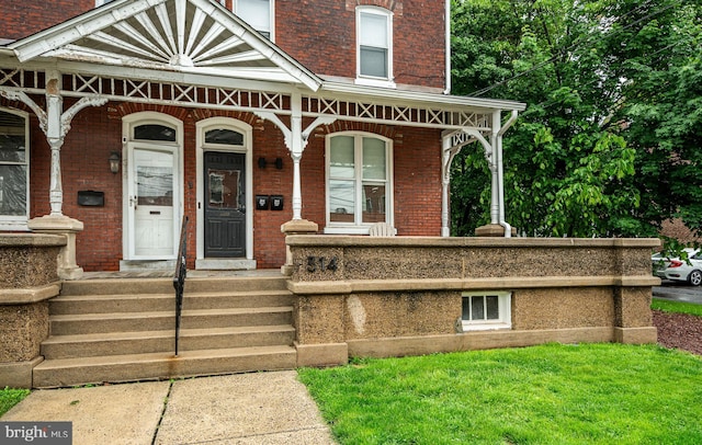 doorway to property with covered porch and brick siding