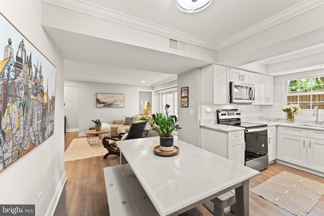 124 Fort Evans Rd SE Unit B, Leesburg, VA 20175 - kitchen with appliances with stainless steel finishes, a sink, crown molding, light wood-style floors, and open floor plan