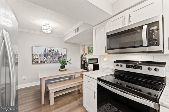 124 Fort Evans Rd SE Unit B, Leesburg, VA 20175 - kitchen with appliances with stainless steel finishes, crown molding, white cabinetry, light wood-style flooring, and decorative backsplash