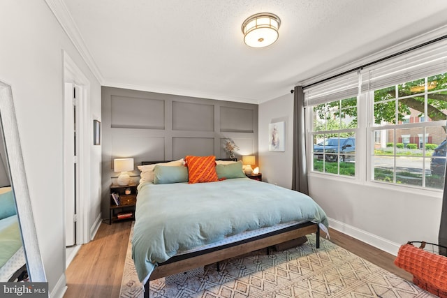 124 Fort Evans Rd SE Unit B, Leesburg, VA 20175 - bedroom with crown molding, multiple windows, baseboards, wood finished floors, and a decorative wall