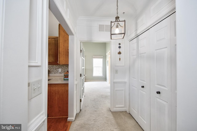 corridor featuring light carpet and crown molding