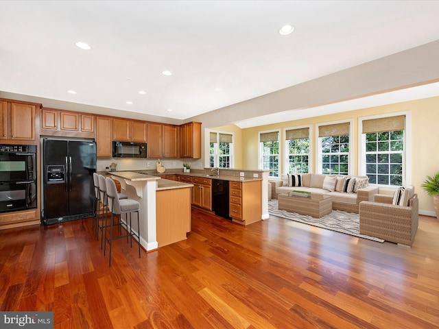 15 Wagon Shed Ln, Middletown, MD 21769 - kitchen featuring black appliances, a sink, a kitchen breakfast bar, open floor plan, and dark wood-style floors