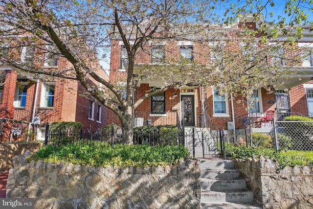 view of property featuring a fenced front yard, brick siding, and a gate