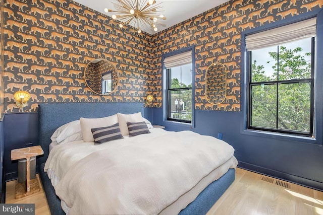 bedroom featuring a chandelier, wood finished floors, multiple windows, and baseboards