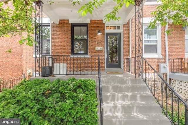 property entrance featuring brick siding and a porch