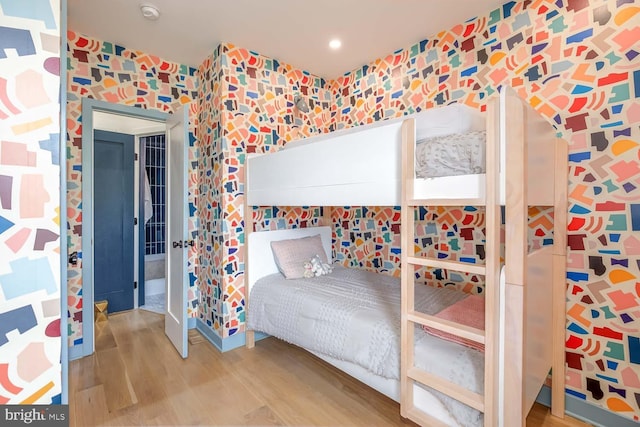 bedroom with wallpapered walls and wood finished floors